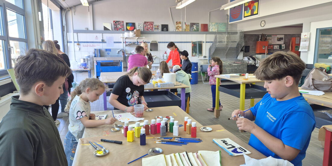 Malerwerkstatt: Kinder gestalten Stoffmäppchen und Buttons und arbeiten kreativ mit Farben