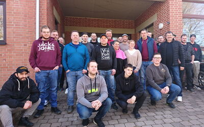 Eine Gruppe von 30 Handwerkern, darunter eine Handwerkerin, hat sich vor der Geschäftsstelle in Frankenberg für ein Gruppenfoto versammelt. Die Teilnehmenden stehen in mehreren Reihen, während einige in der ersten Reihe hocken.