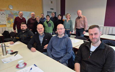Die Teilnehmenden des Refresher-Seminars: Einige sitzen in der vorderen Reihe, andere stehen dahinter. Links stehend Dozent Wolfgang Winkelmann.