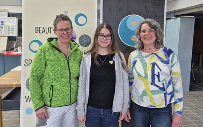 Emily Helmecke mit Ausbilderin und Sozialpädagogin vor den von ihr gestalteten Prüfungswänden.