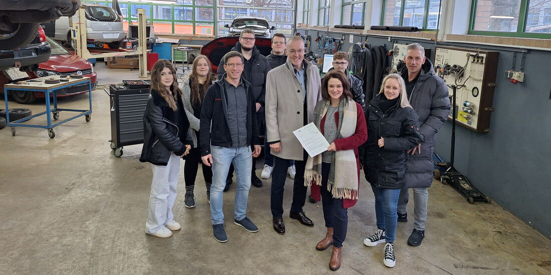 In der Kfz-Werkstatt des BBZ Korbach stehen von rechts Kai Bremmer, Kim Fachinger, Maria Djambazov, Bernd Wilke und Tobias Knipp sowie Auszubildende zu einem Foto zusammen.