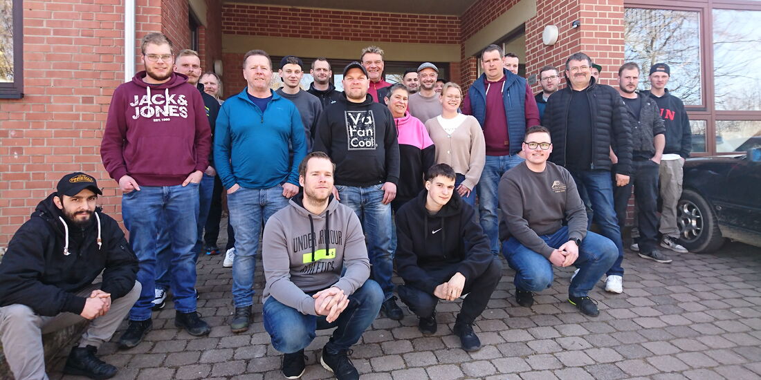 Eine Gruppe von 30 Handwerkern, darunter eine Handwerkerin, hat sich vor der Geschäftsstelle in Frankenberg für ein Gruppenfoto versammelt. Die Teilnehmenden stehen in mehreren Reihen, während einige in der ersten Reihe hocken.