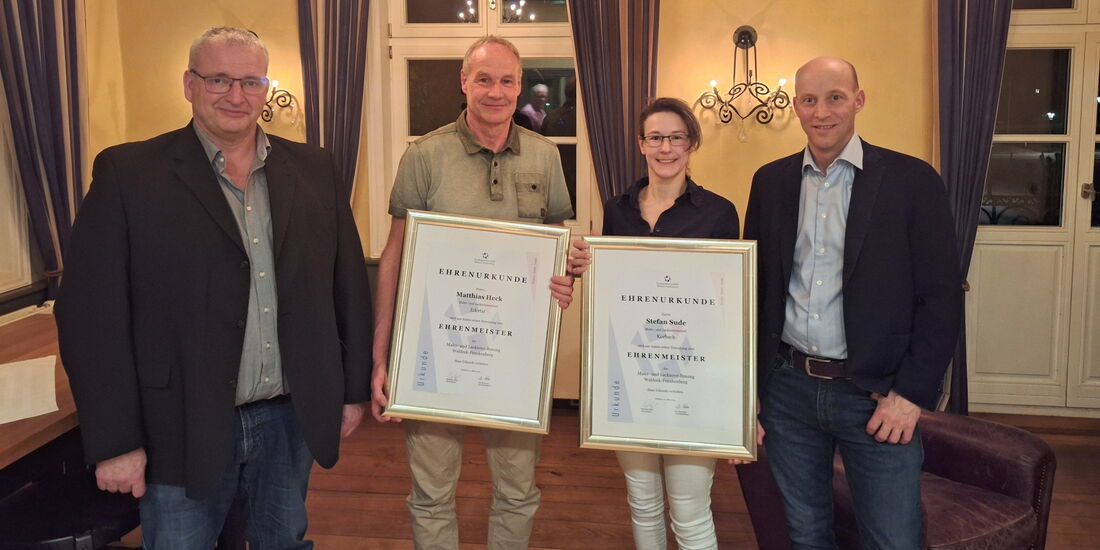 Vier Mitglieder der Innung stehen im Restaurant Friedrichs nebeneinander, zwei halten Ehrenurkunden, alle blicken freundlich in die Kamera.