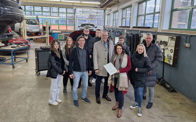 In der Kfz-Werkstatt des BBZ Korbach stehen von rechts Kai Bremmer, Kim Fachinger, Maria Djambazov, Bernd Wilke und Tobias Knipp sowie Auszubildende zu einem Foto zusammen.