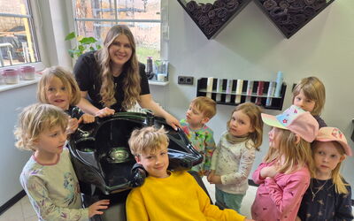 Friseurmeisterin zeigt Kita-Kindern (3–6) den Waschplatz; jedes Kind durfte den Friseurstuhl ausprobieren.