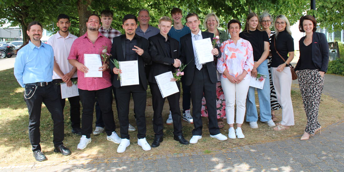 Ein Teil der Absolvent*innen steht mit Lehrkräften im Gruppenbild, alle lächeln – sichtbare Freude nach bestandenen Schulabschlüssen.